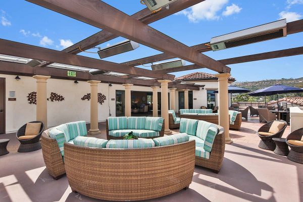 Rooftop patio sitting area with round couches, patio tables and chairs, all overlooking the surrounding hills.