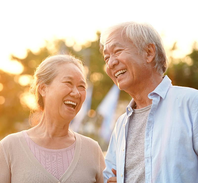 Smiling older Asian couple in late afternoon sunlight.