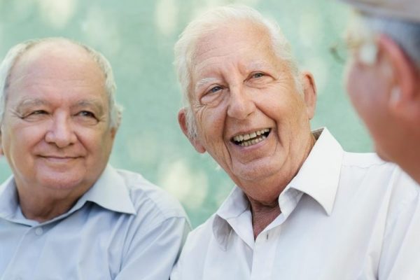 Group of older men smiling and laughing with one another.