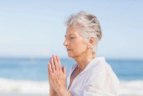 Older woman doing Yoga at the beach.