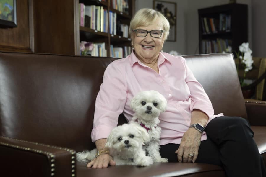 Lovely older woman sitting on a leather sofa with her two little white dogs.