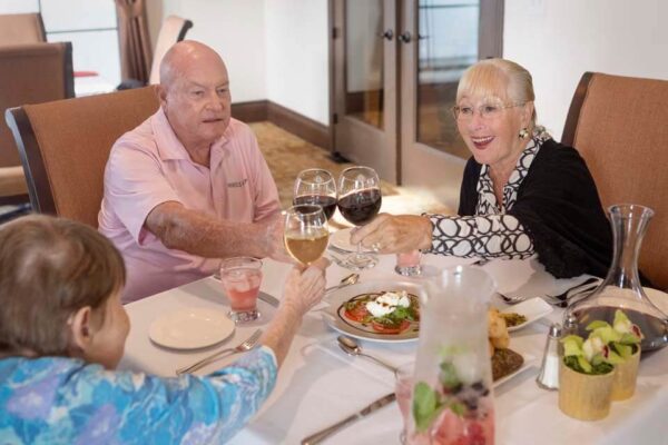 Crestavilla residents toasting with glasses of wine at an elegant dinner.