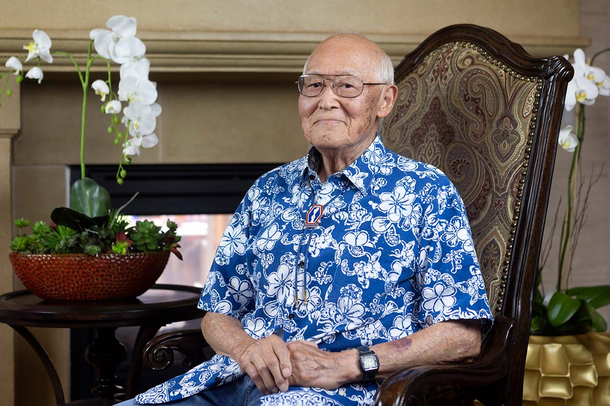Crestavilla resident Mr. Sato in a blue and white flowered shirt sitting in a high-backed chair.