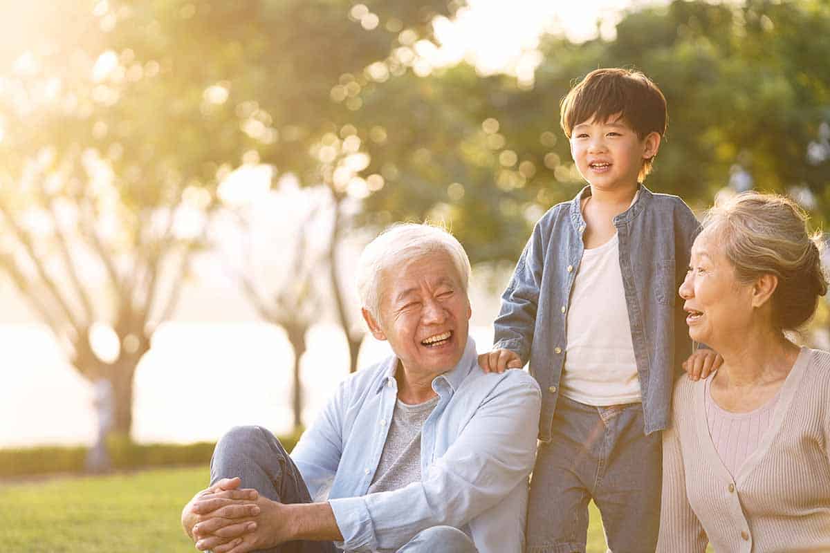 Older Asian couple with grandson at the park.